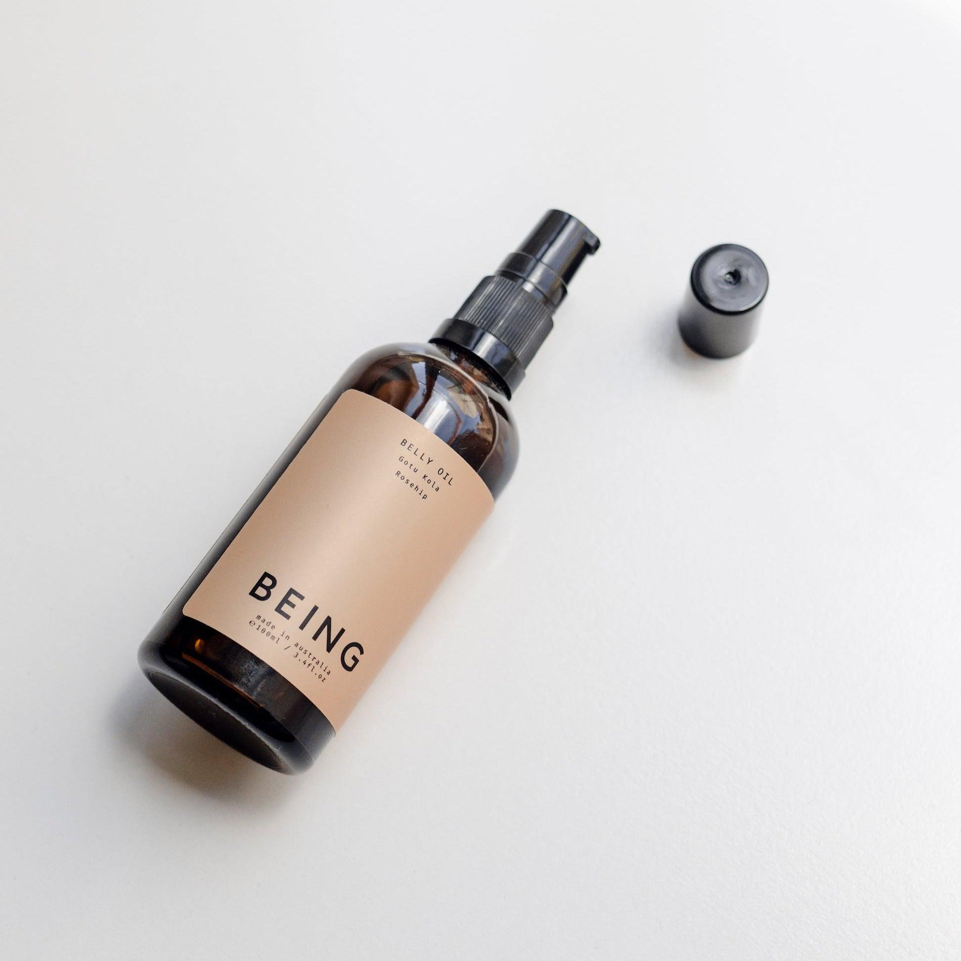 A bottle of Being Skincare Belly Oil on a white surface.