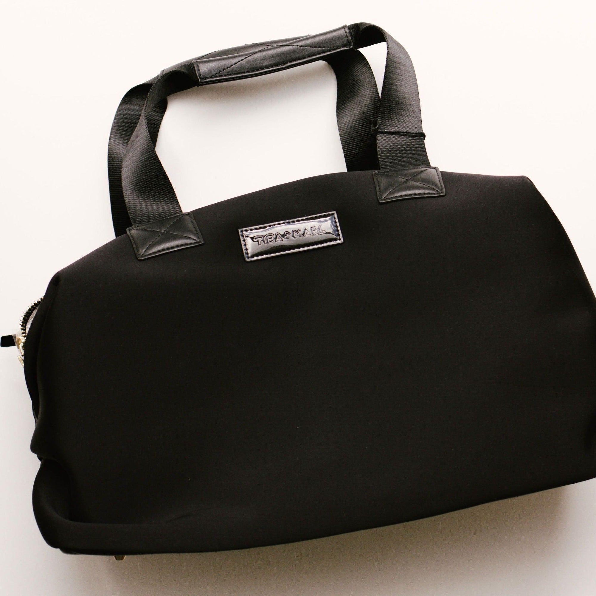 A sleek and compact every-day version of our best selling RAF WEEKENDER. Smaller but perfectly formed and includes all original internal functionality.   This hard-working holdall gets a sports-lux make-over in sleek Black scuba fabric, paired with lux gold hardware. The perfect size to fit all your essential items for a day out, it also doubles up as a stylish work bag, hand bag or overnight bag.