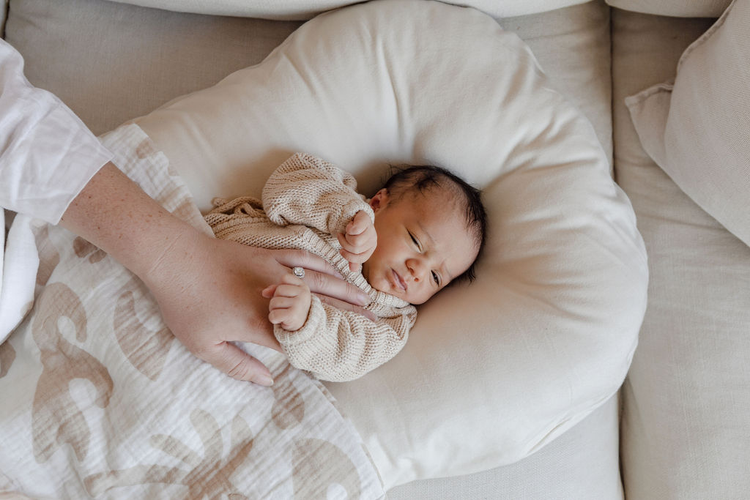 A baby is being held by a woman on a couch.