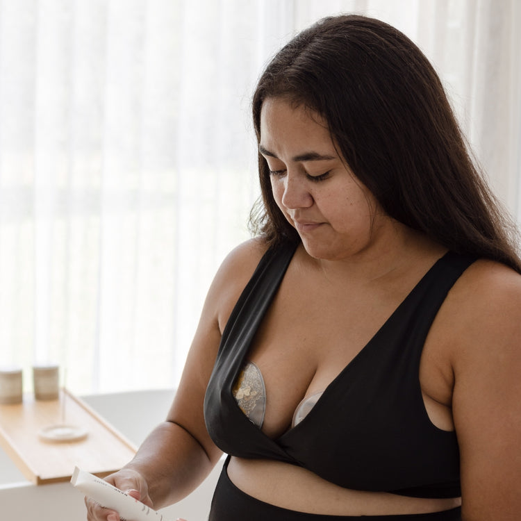 A woman in a black bra looking at her cell phone.