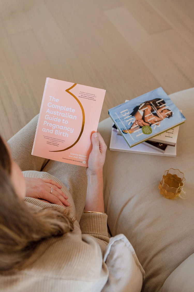 A woman is sitting on a couch reading a book.