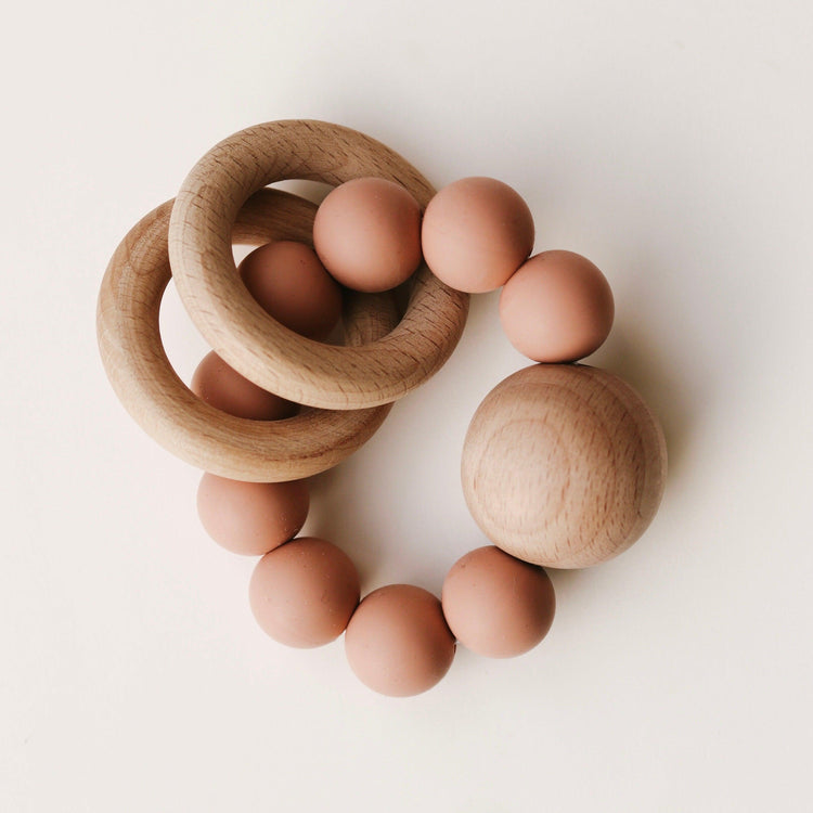 A set of Dove & Dovelet Wooden Silicone Teethers on a white surface.