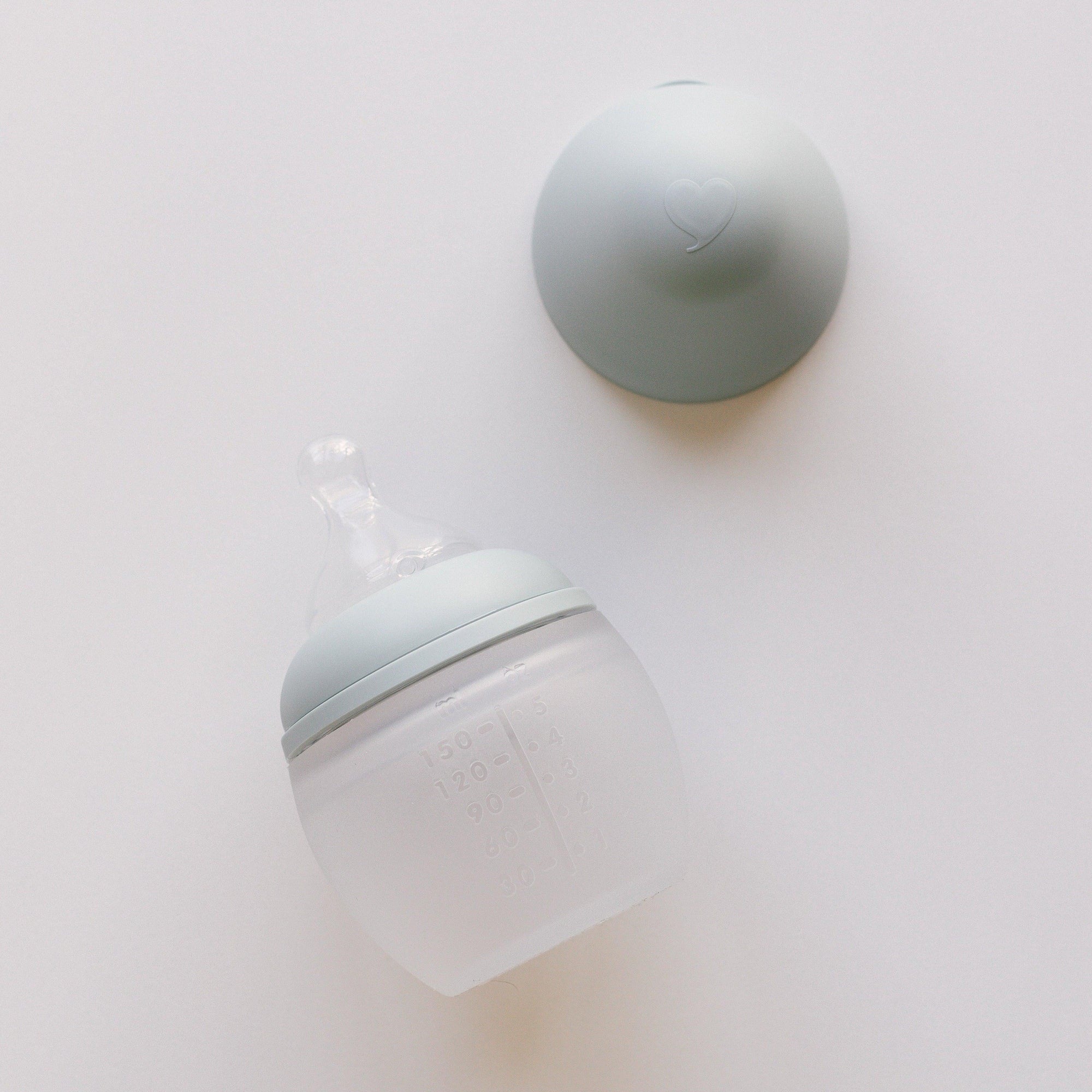 An Elhée France BibRond ivy green baby bottle on a white surface.